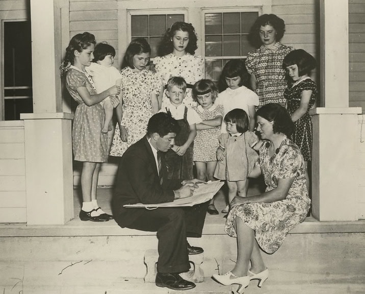 Black and white photo of a 1940 census worker counts a family, asking 50 questions in the longest census to date.